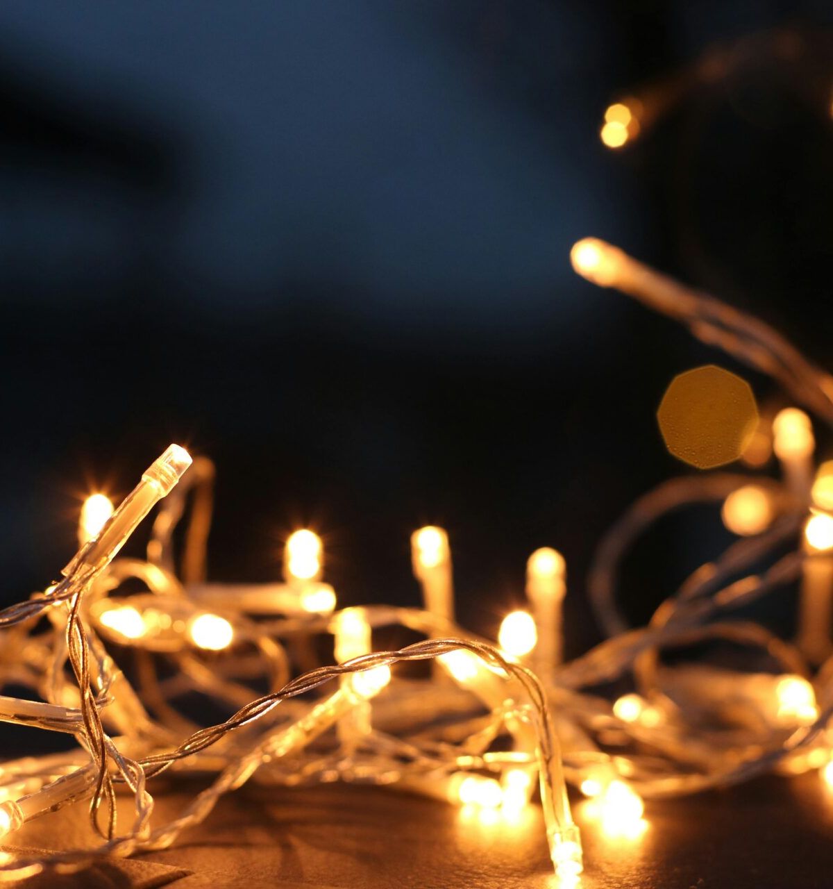 Optima Lakeview® Apartments in Chicago, IL Close-up of glowing yellow string lights adds a cozy touch to home decor against a dark, blurred background.