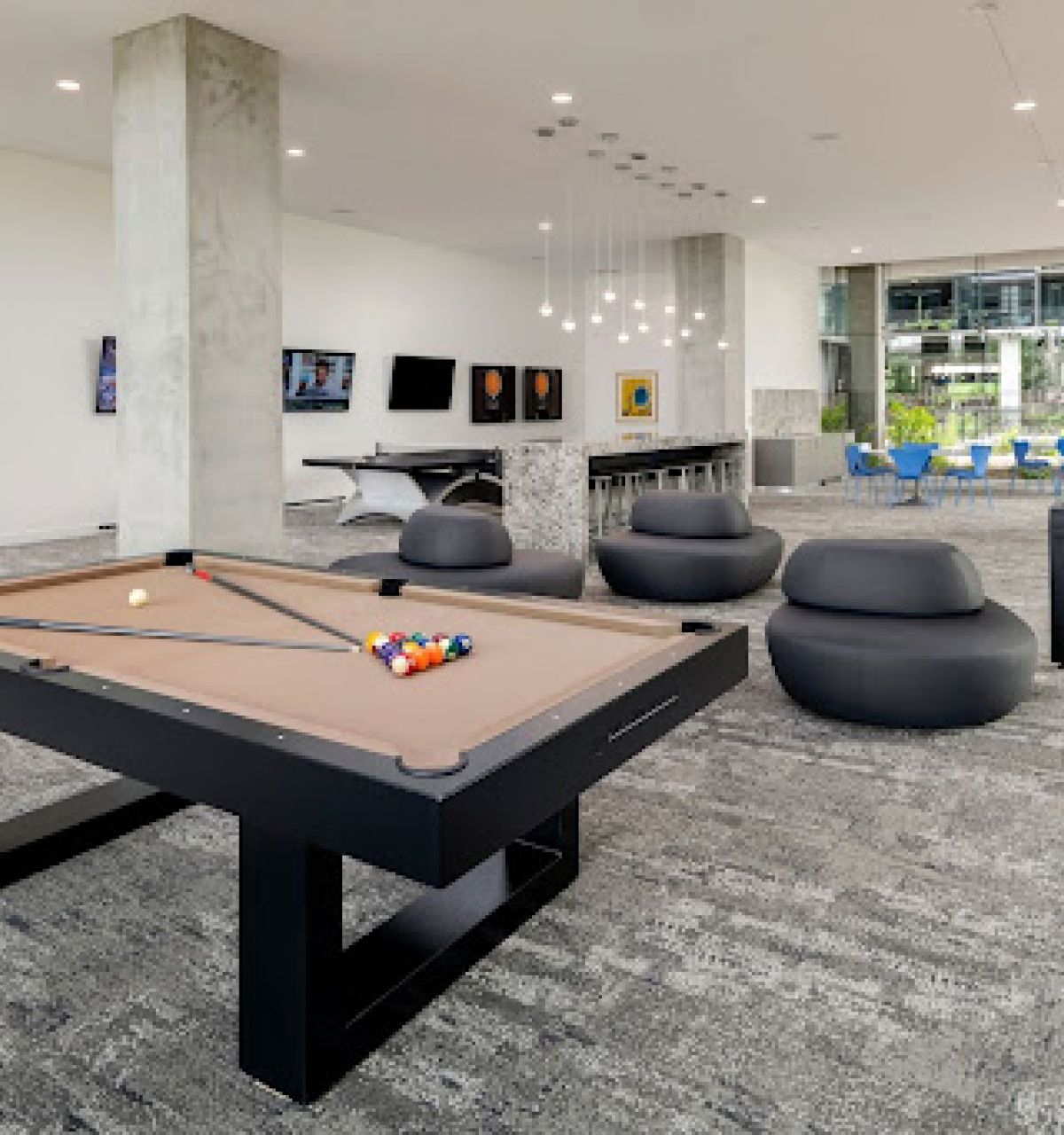 Optima Lakeview® Apartments in Chicago, IL Modern lounge with a pool table, seating, large windows, artwork, and shuffleboard for extra fun.