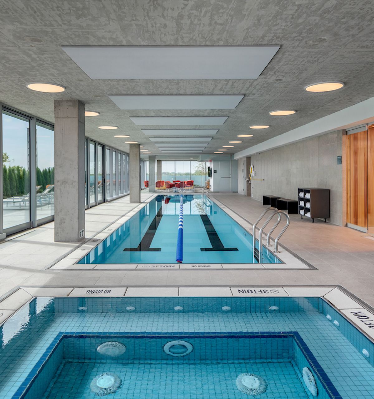 Optima Lakeview® Apartments in Chicago, IL Enjoy Winter Wellness at this modern indoor pool and hot tub, featuring sunlit windows and cozy poolside lounge chairs.