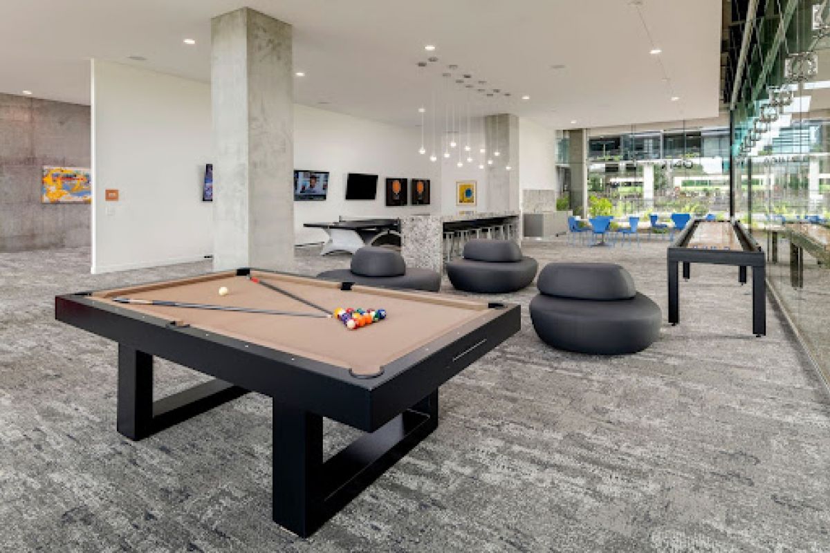 Optima Lakeview® Apartments in Chicago, IL Modern lounge with a pool table, seating, large windows, artwork, and shuffleboard for extra fun.