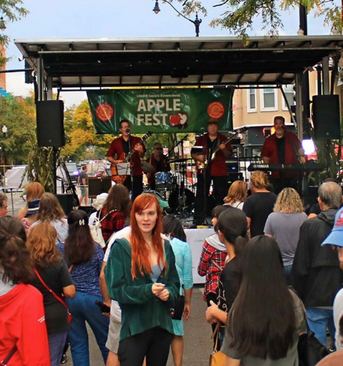 Optima Lakeview® Apartments in Chicago, IL Crowd gathers at an outdoor Apple Fest in autumn, watching a live band perform on a Chicago street stage.