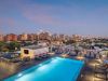 Optima Lakeview® Apartments in Chicago, IL Experience effortless wellness by the rooftop pool as city lights glow and sunset transforms the skyline, lounge chairs inviting pure relaxation.