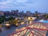 Optima Lakeview® Apartments in Chicago, IL Rooftop lounge at Optima Lakeview with fire pits, tables, and a pool overlooking the city skyline at dusk.