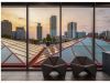 Optima Lakeview® Apartments in Chicago, IL Two modern chairs by large windows, welcoming you home as the city skyline glows with a good night sunset above geometric rooftops.