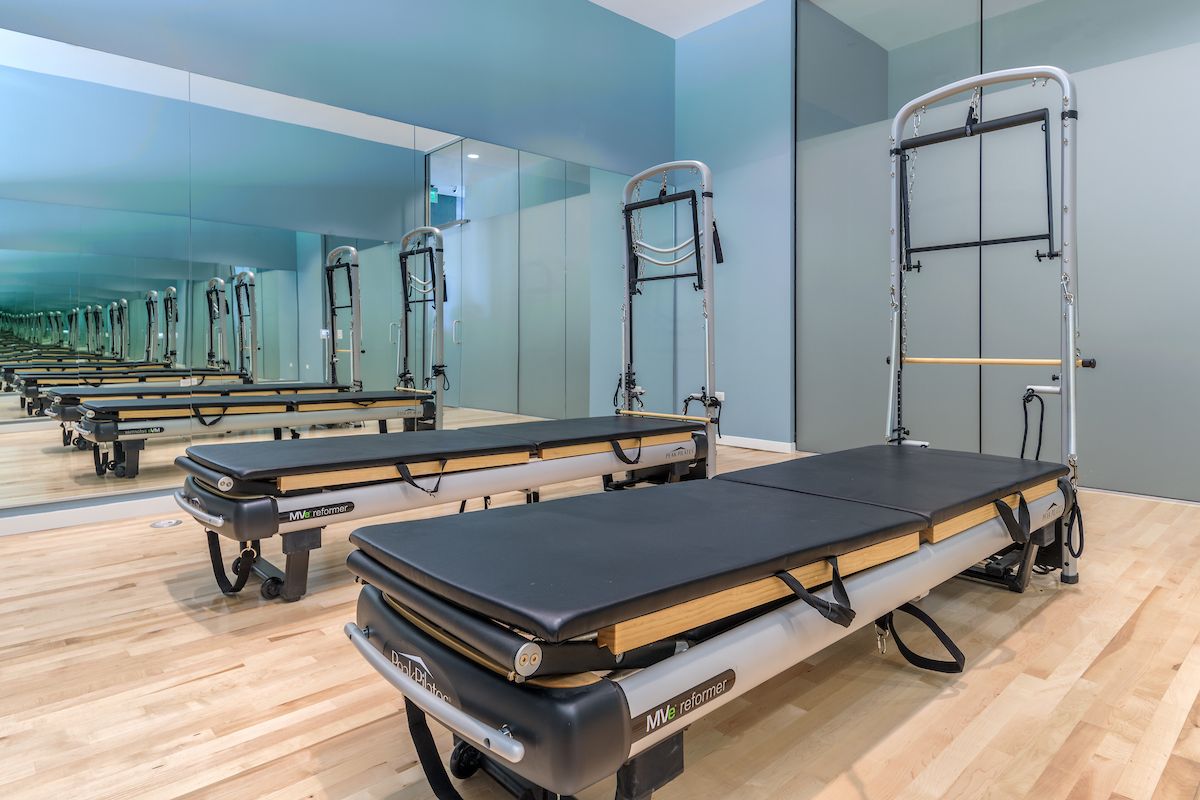 Optima Lakeview® Apartments in Chicago, IL Two Pilates reformer machines in a bright studio with mirrored walls and a light wood floor for ultimate health benefits.