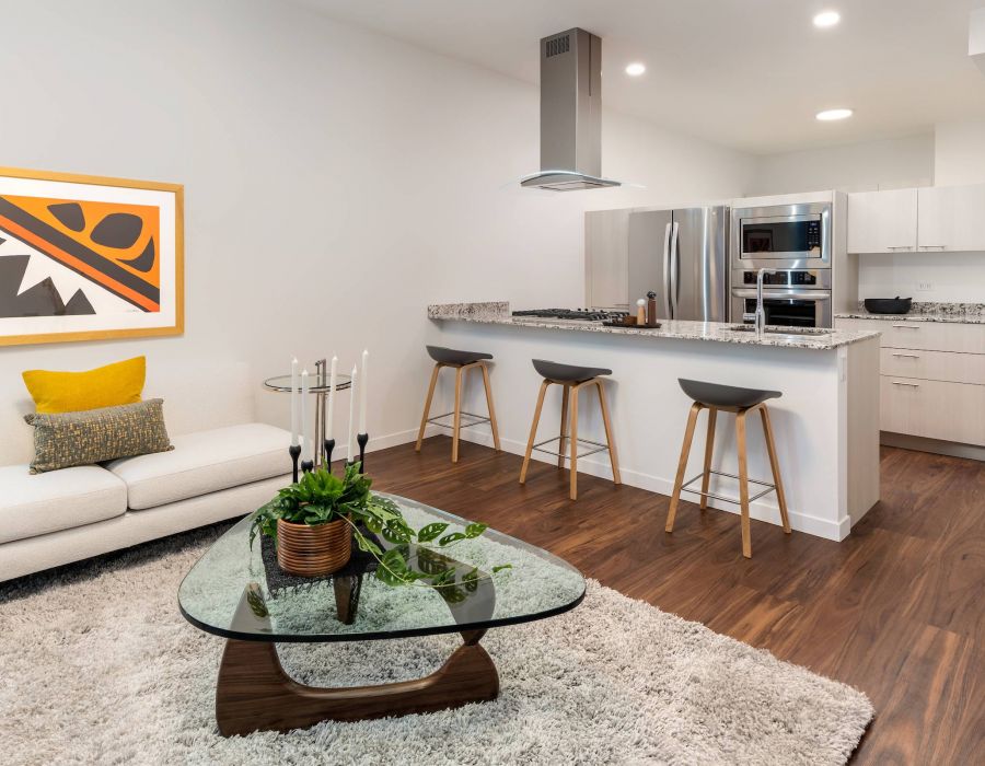 Optima Lakeview® Apartments in Chicago, IL Modern open-concept kitchen and living room with white walls, wood floors, and contemporary decor.