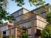 Optima Lakeview® Apartments in Chicago, IL Modern glass and brick apartment building in the Optima Community, surrounded by green trees under a clear blue sky.