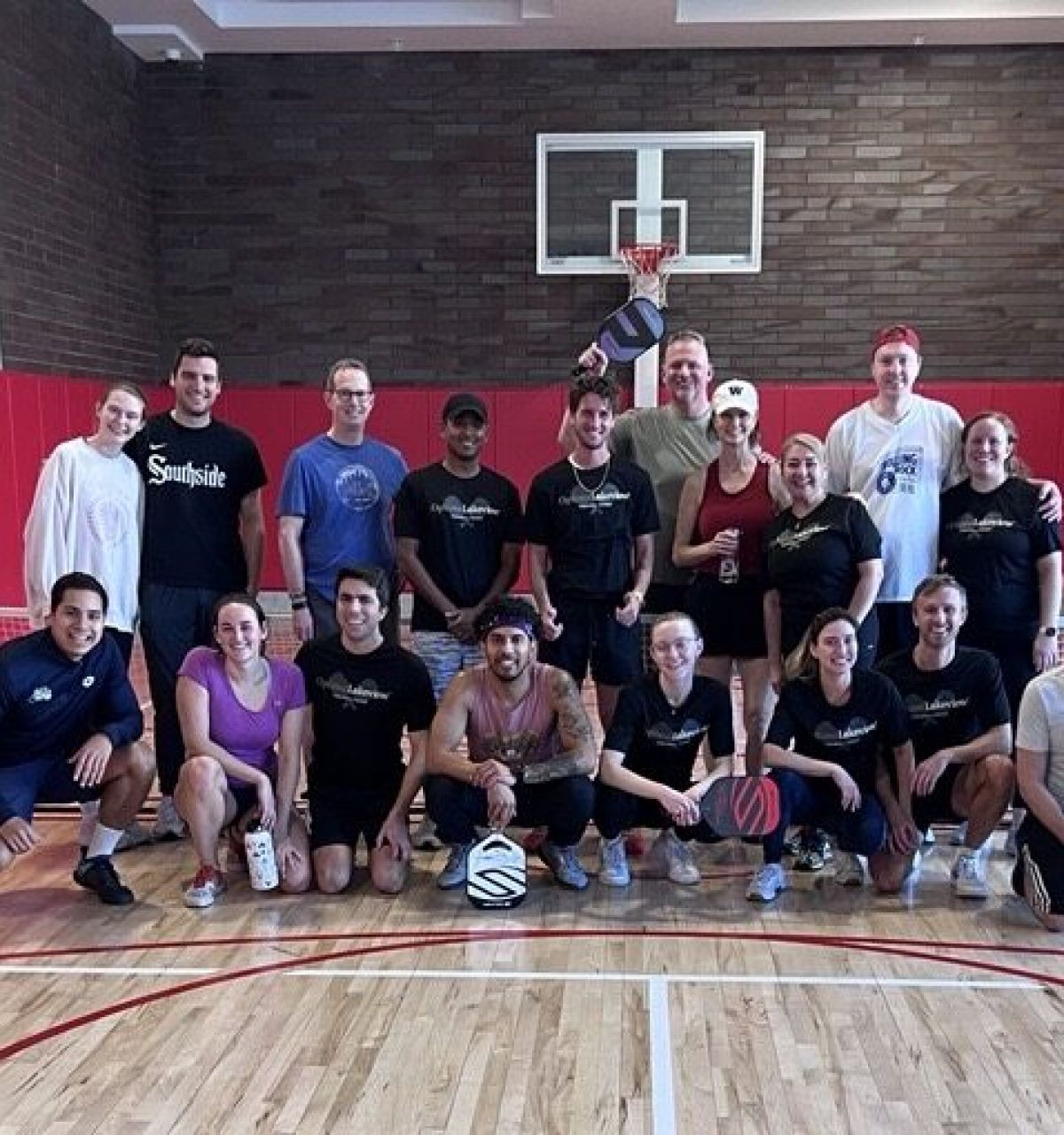 Optima Lakeview® Apartments in Chicago, IL A group of eighteen pickleball players posing for a photo on an indoor court.