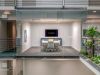 Optima Lakeview® Apartments in Chicago, IL Glass-walled conference room by Optima features modern work design, with chairs, TV, and views of a gym area amidst plants and stylish decor.