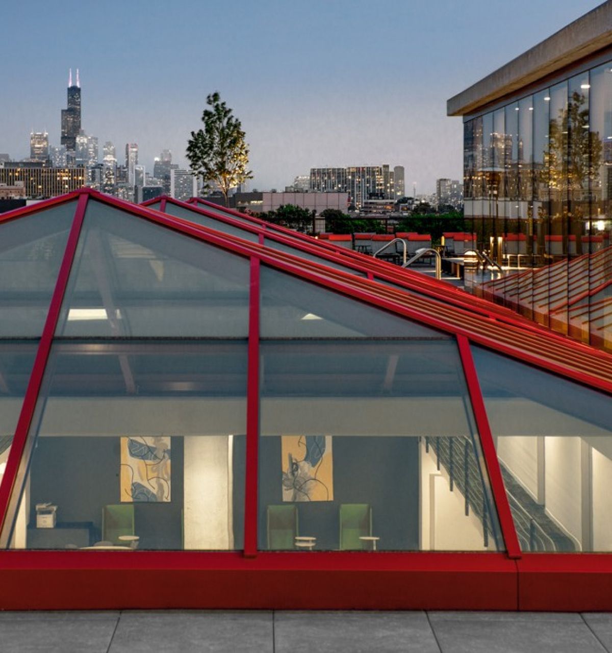 Optima Lakeview® Apartments in Chicago, IL A glass-roofed building by Optima Living frames everyday beauty against a city skyline at dusk.