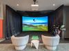 Optima Lakeview® Apartments in Chicago, IL Two gray chairs face a golf simulator screen, perfect for indoor golf, with clubs on the right and a small white table in between.