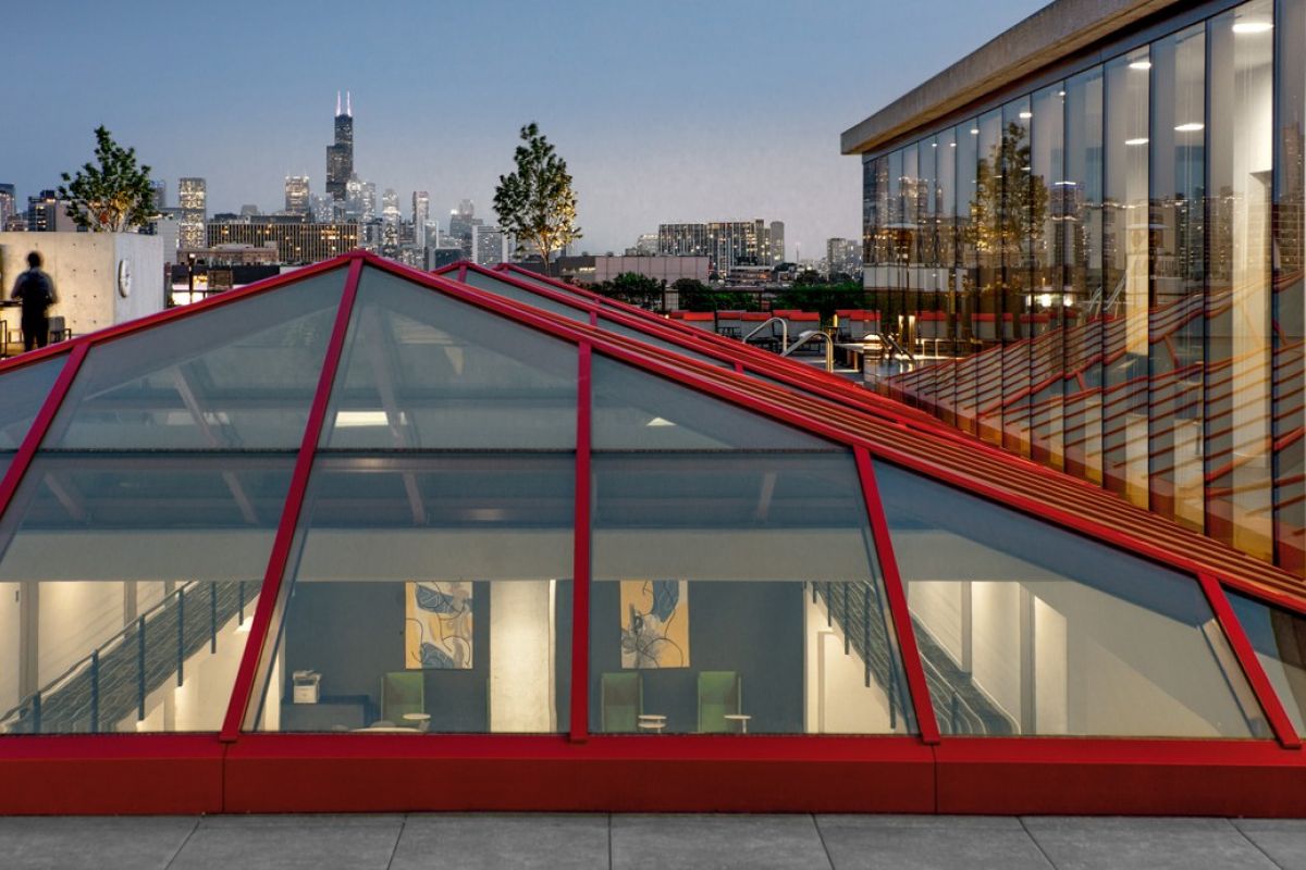 Optima Lakeview® Apartments in Chicago, IL A glass-roofed building by Optima Living frames everyday beauty against a city skyline at dusk.