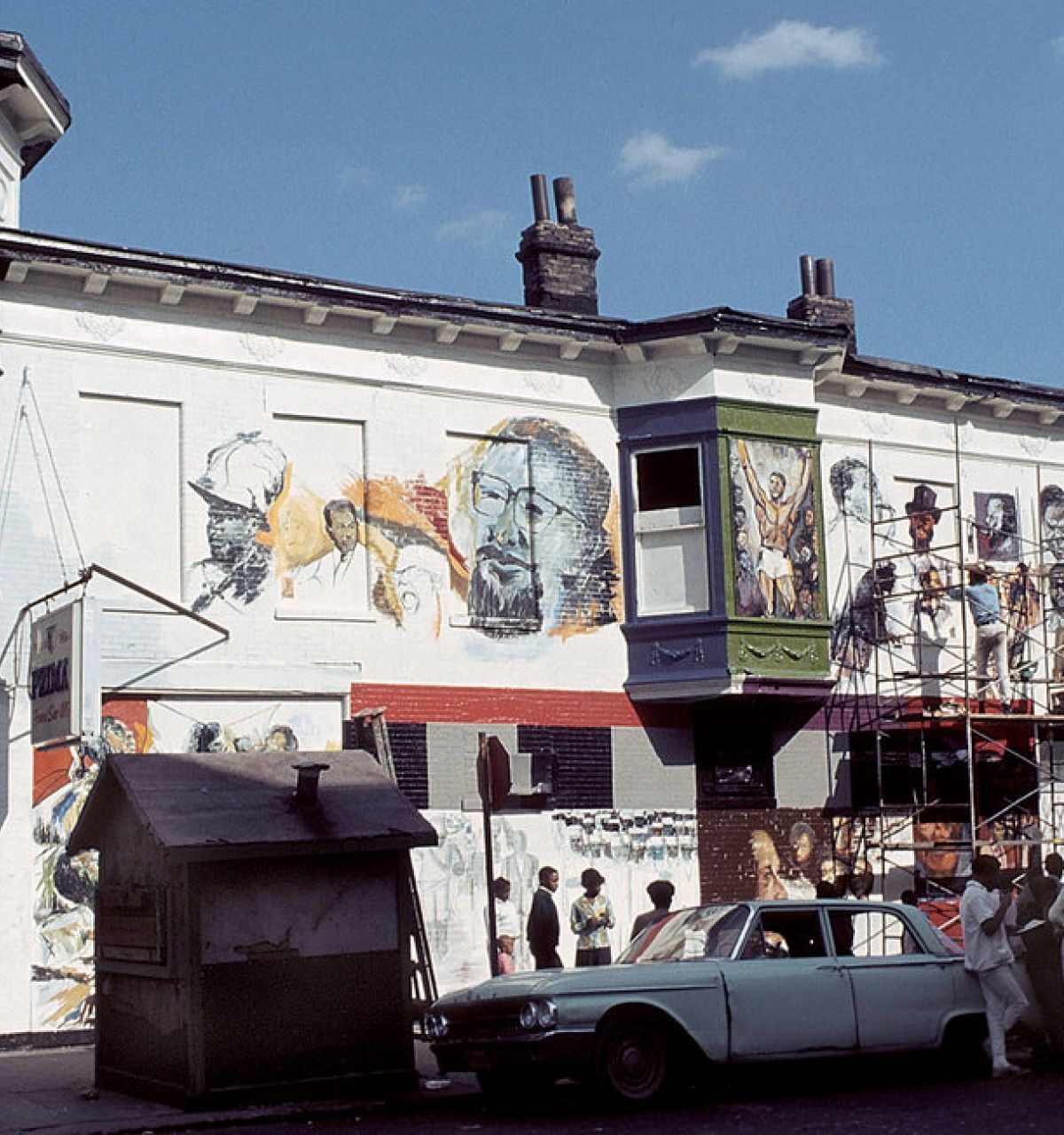 Optima Lakeview® Apartments in Chicago, IL Artists from the Chicago Public Art Group paint a mural as a crowd watches; a vintage car marks over 50 years of public art.