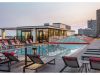 Optima Lakeview® Apartments in Chicago, IL Enjoy stunning evenings on the Sky Deck, featuring a rooftop pool, lounge chairs, red accents, and city views at sunset.