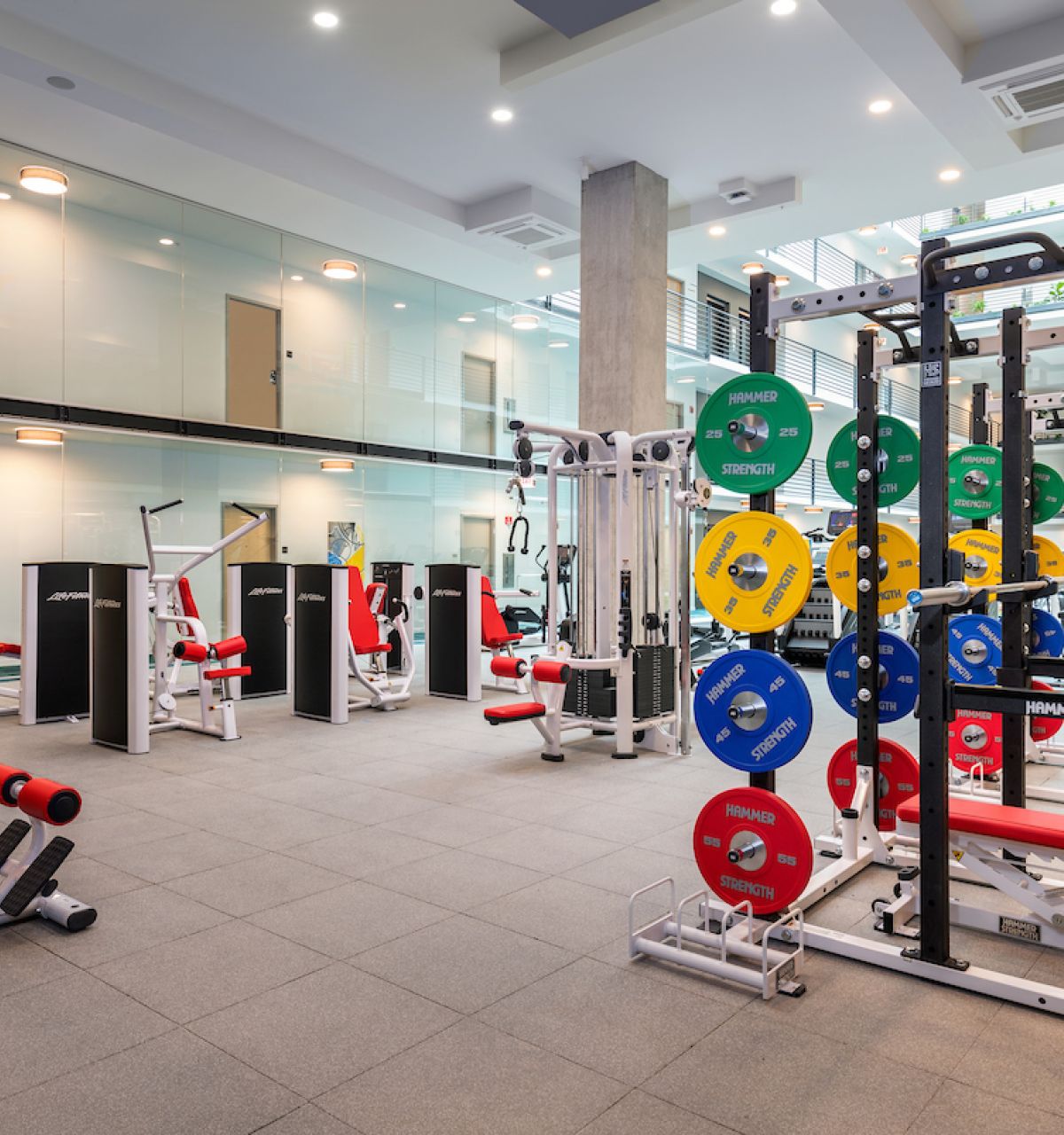 Optima Lakeview® Apartments in Chicago, IL Modern fitness center with weightlifting racks, colorful plates, and various machines to support your daily habit in a spacious room.