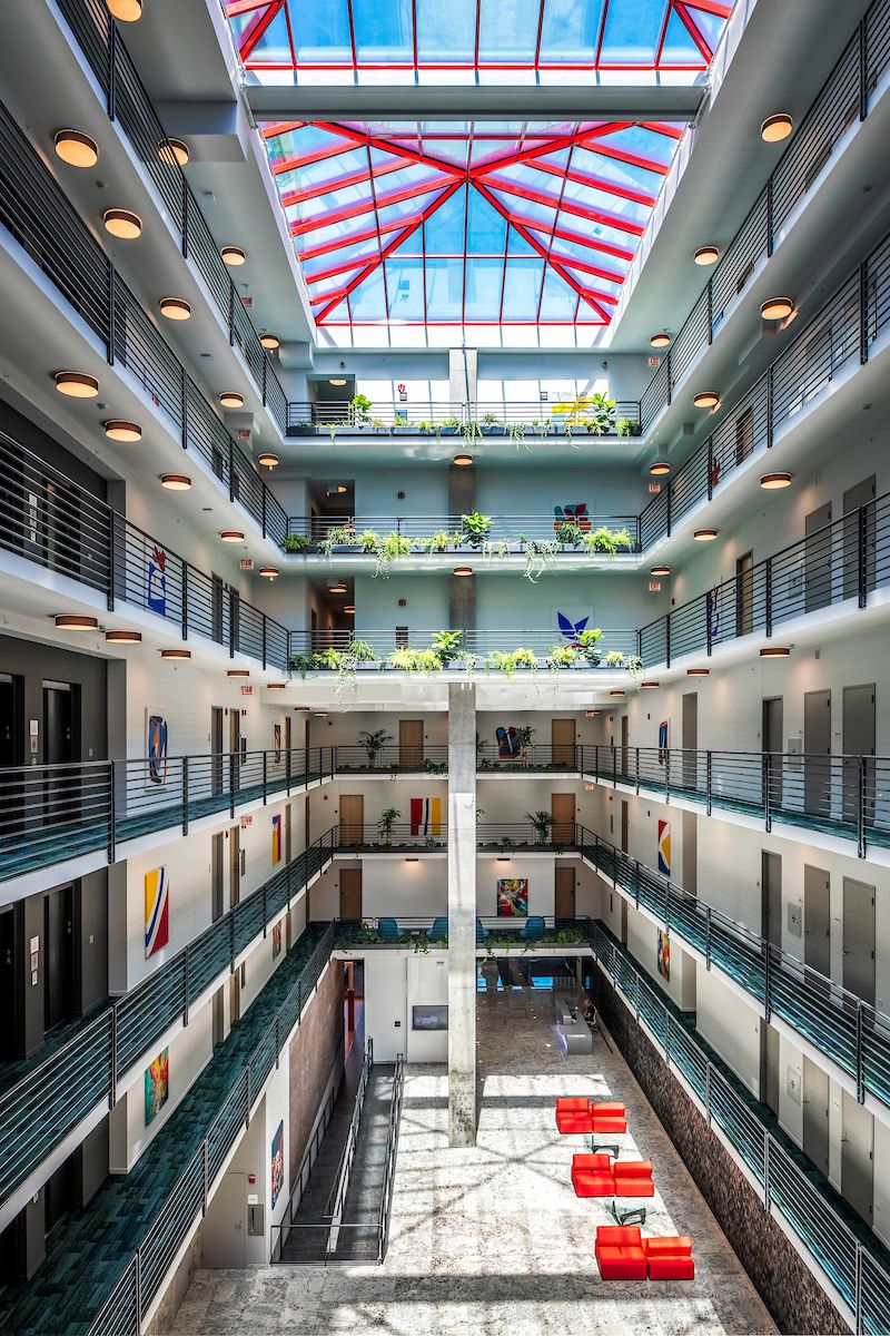 Optima Lakeview® Apartments in Chicago, IL Four-story modern atrium with red seating, plants, skylight, and balcony railings on each level.