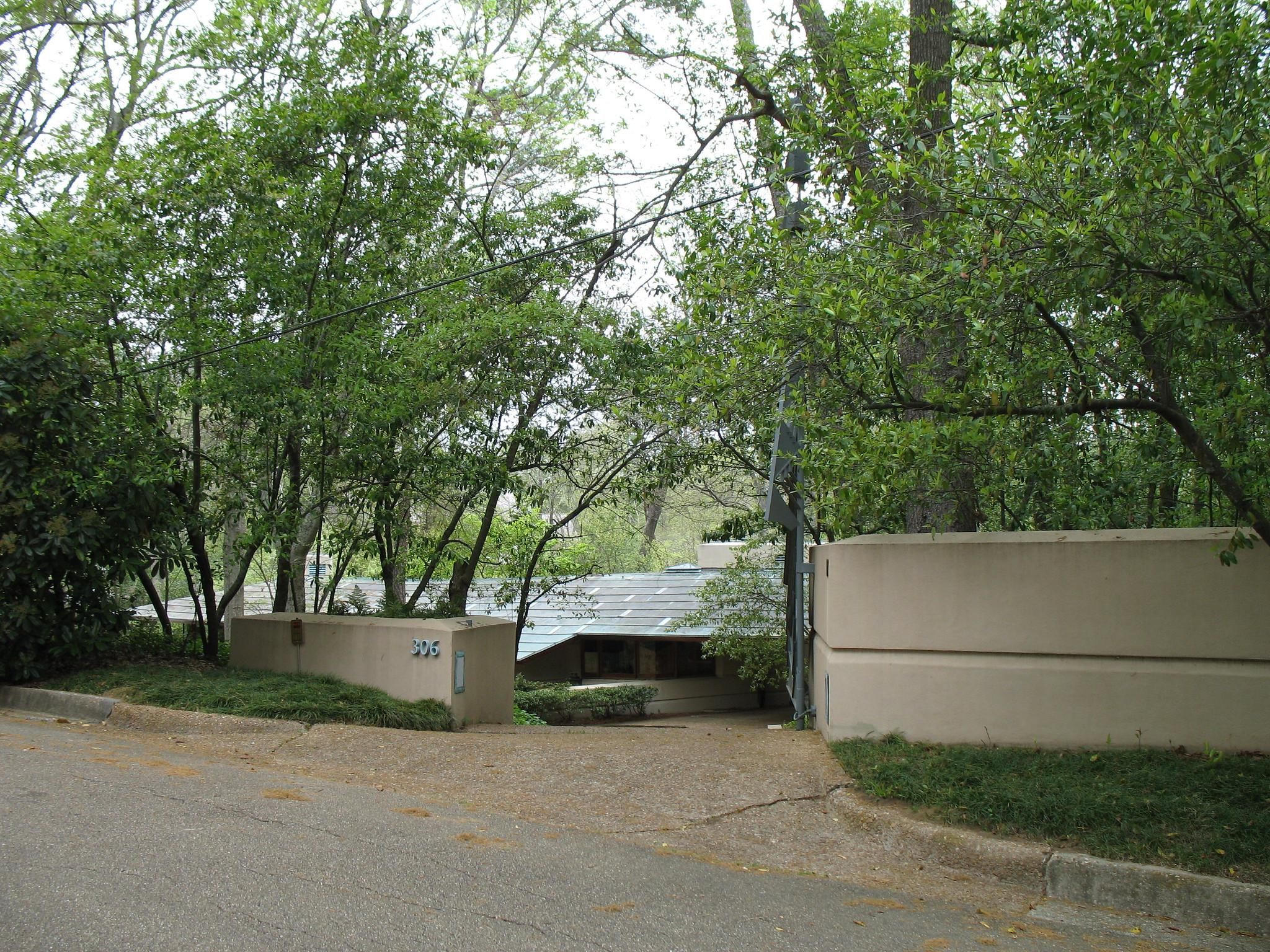 Optima Lakeview® Apartments in Chicago, IL A modern house with a curved wall, echoing the legacy of Modernism; trees partially obscure the entrance from the street.