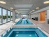 Optima Lakeview® Apartments in Chicago, IL Enjoy Winter Wellness at this modern indoor pool and hot tub, featuring sunlit windows and cozy poolside lounge chairs.