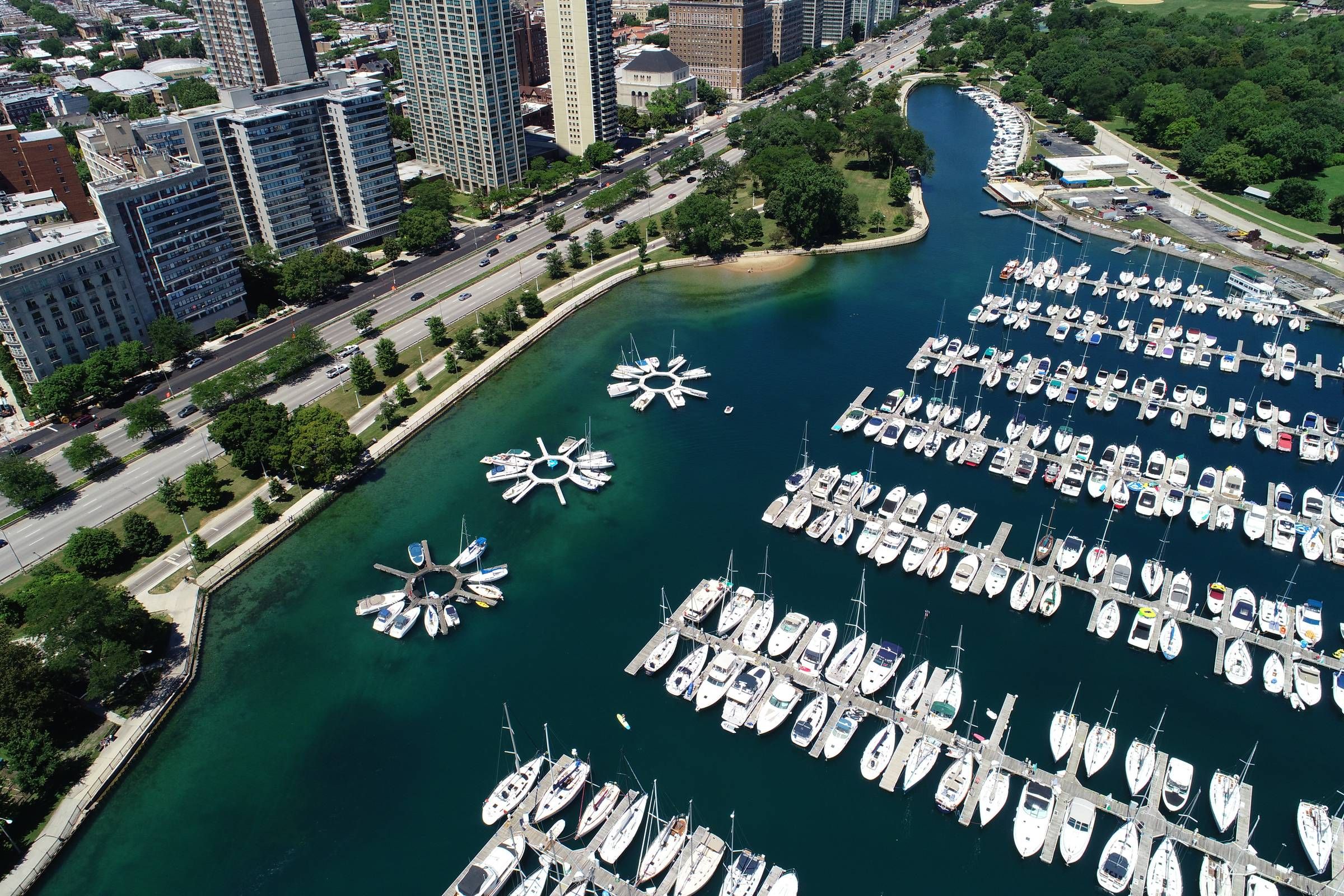 Optima Lakeview® Apartments in Chicago, IL Aerial view of a marina with many boats docked near a city and a waterfront road.