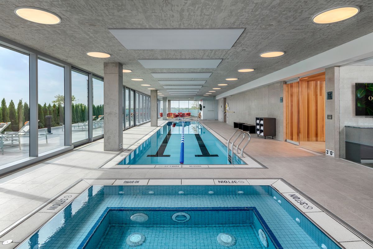 Optima Lakeview® Apartments in Chicago, IL Enjoy Winter Wellness at this modern indoor pool and hot tub, featuring sunlit windows and cozy poolside lounge chairs.