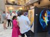 Optima Lakeview® Apartments in Chicago, IL People view colorful abstract art at an Optima Communities gallery celebration, while others mingle and enjoy the lively event in the background.
