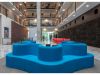 Optima Lakeview® Apartments in Chicago, IL Modern atrium with Optima's lobbies-inspired blue seating, red sofas, and striking multi-story walkways above.