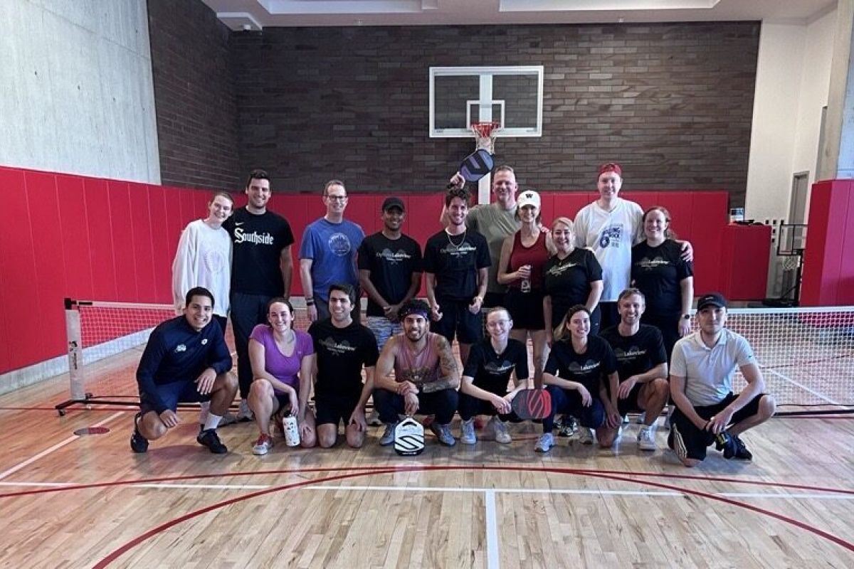 Optima Lakeview® Apartments in Chicago, IL A group of eighteen pickleball players posing for a photo on an indoor court.