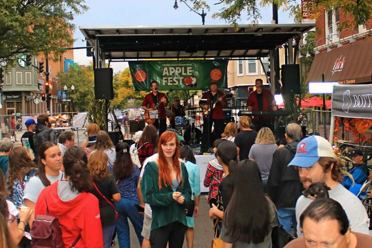 Optima Lakeview® Apartments in Chicago, IL Crowd gathers at an outdoor Apple Fest in autumn, watching a live band perform on a Chicago street stage.