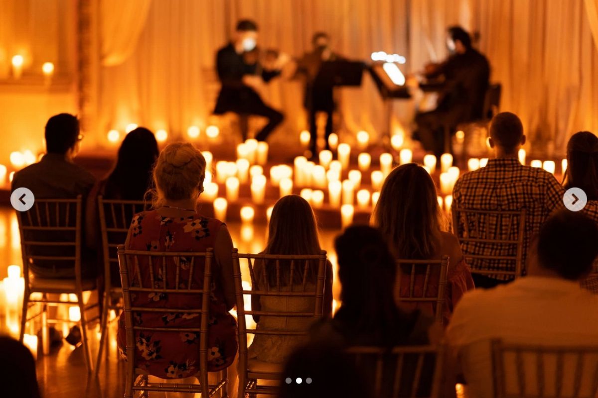 Optima Lakeview® Apartments in Chicago, IL Audience enjoys a mesmerizing Candlelight Concerts string quartet in Chicago, surrounded by glowing candles in a warmly lit room.
