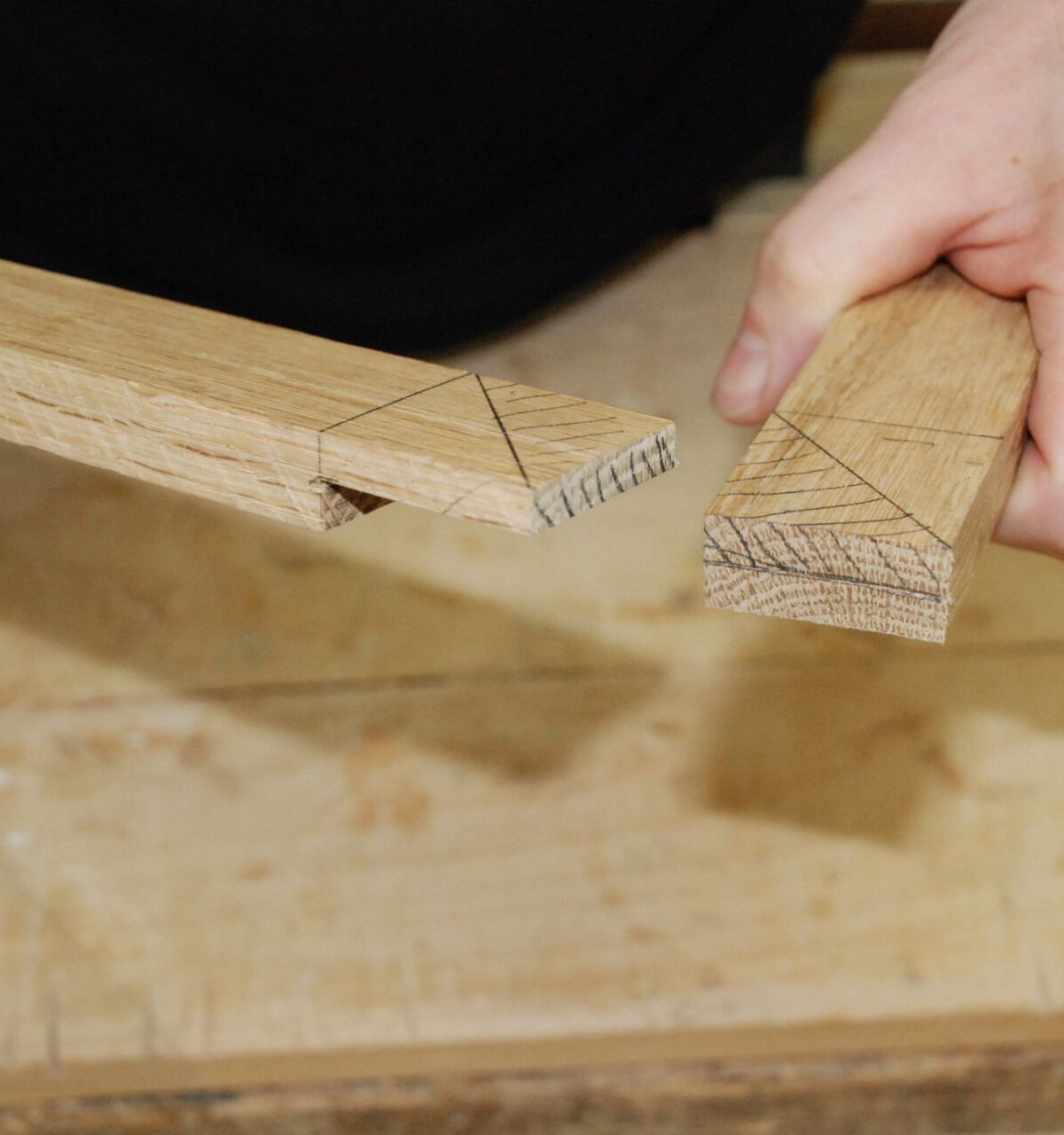 Optima Lakeview® Apartments in Chicago, IL Two hands hold dovetail-jointed pieces, showcasing skills learned at Chicago School of Woodworking classes.