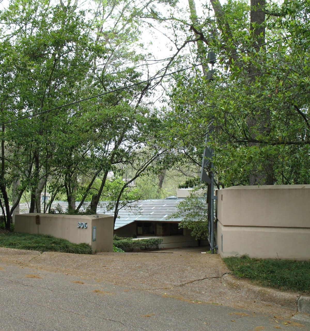 Optima Lakeview® Apartments in Chicago, IL A modern house with a curved wall, echoing the legacy of Modernism; trees partially obscure the entrance from the street.