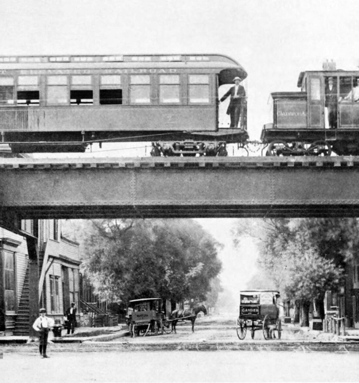 Optima Lakeview® Apartments in Chicago, IL Historic black-and-white photo of a train riding the rails on the Chicago “L” above a bustling street scene.