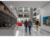 Optima Lakeview® Apartments in Chicago, IL Modern office lobby at Optima Community with people living daily life, a receptionist, and colorful art on the walls.