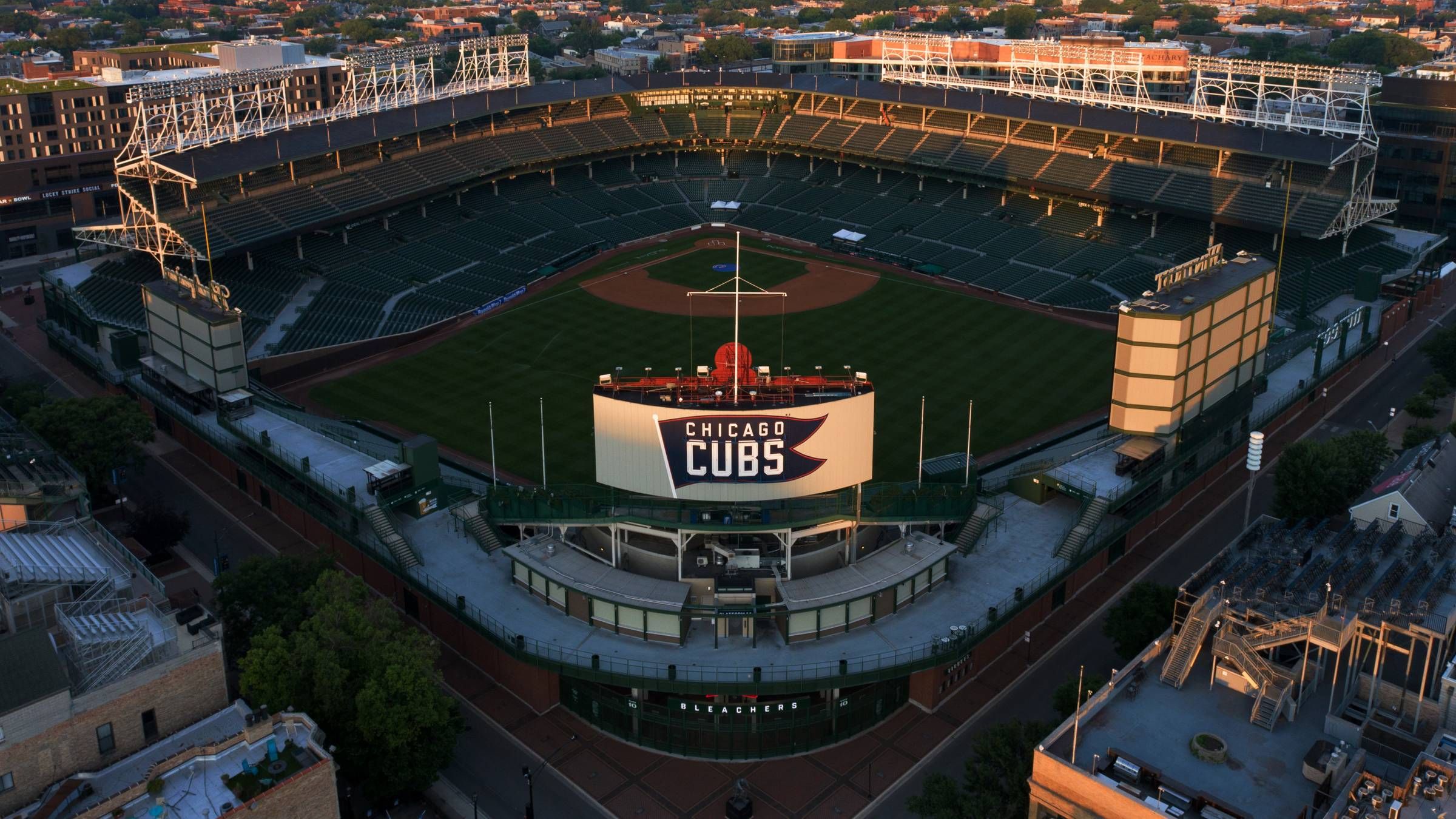 Optima Lakeview® Apartments in Chicago, IL Aerial view of an empty Wrigley Field baseball stadium with a “Chicago Cubs” sign on the scoreboard.