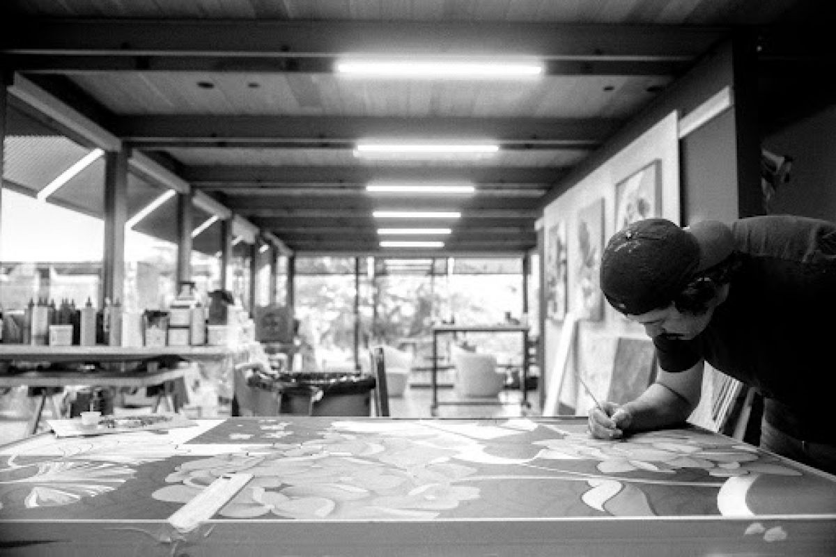 Optima Lakeview® Apartments in Chicago, IL A person in a cap paints a large floral artwork on a table in the bright Ellison Keomaka Art studio at Optima Lakeview.