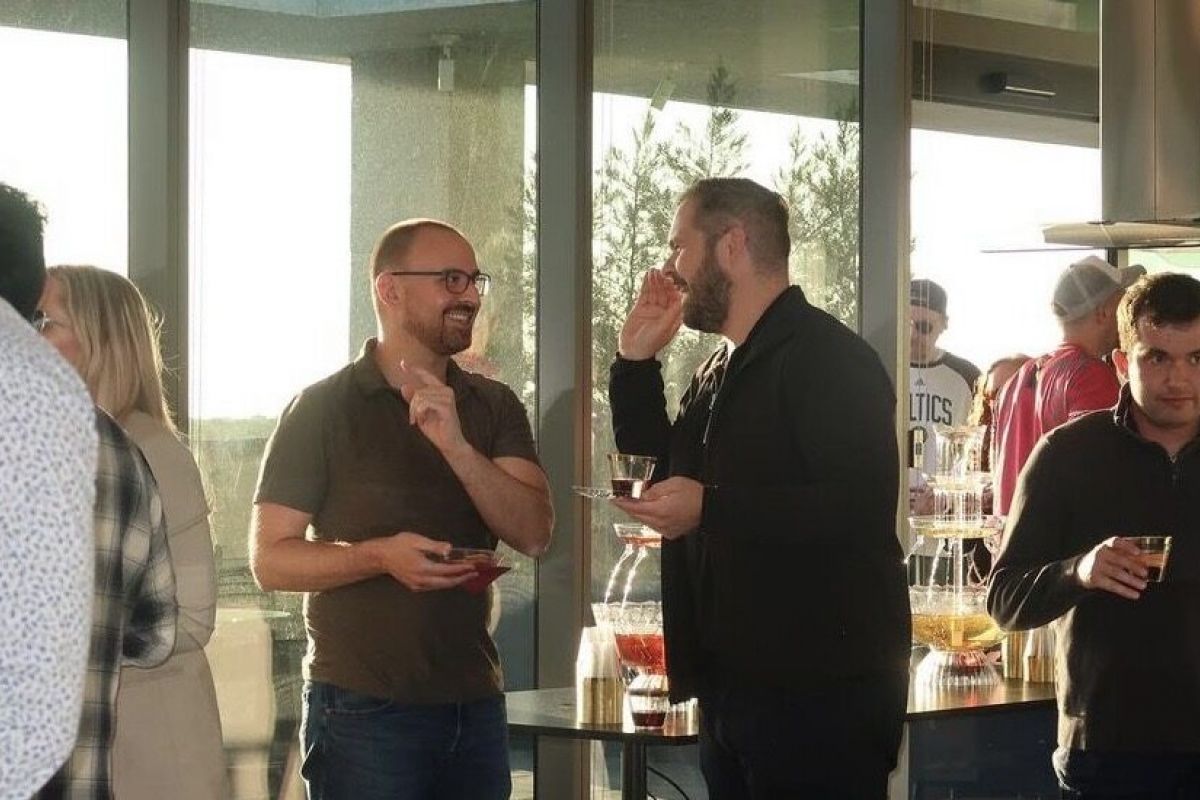 Optima Lakeview® Apartments in Chicago, IL People enjoy perks as they socialize at a sunny Optima Connect indoor gathering with drinks and snacks near large windows.