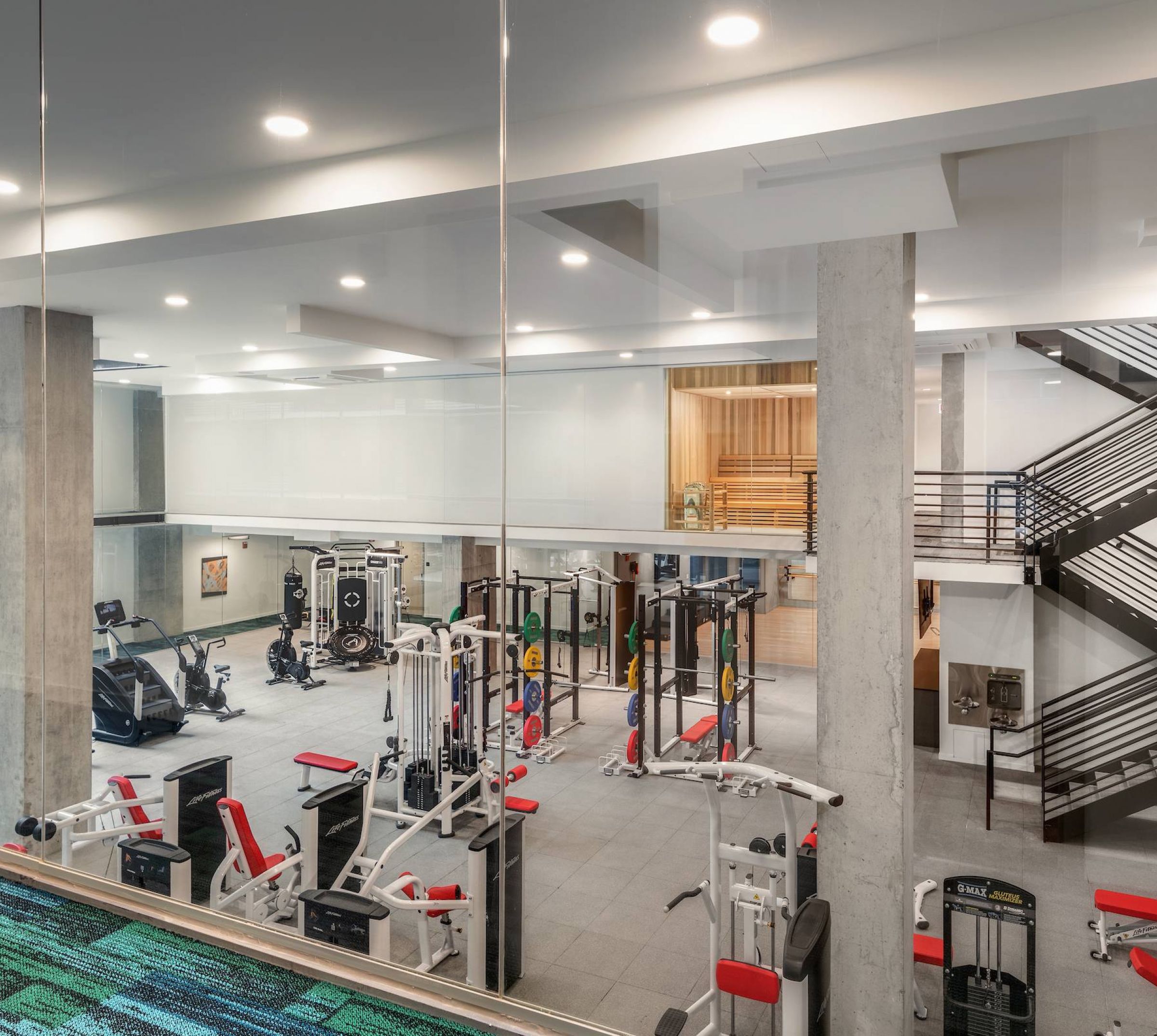 Optima Lakeview® Apartments in Chicago, IL Modern gym with various exercise machines, strength equipment, and staircases in a spacious, well-lit area.
