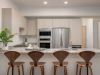 Optima Lakeview® Apartments in Chicago, IL Modern kitchen design with light wood cabinets, stainless steel appliances, and four wooden barstools at an Optima granite island.