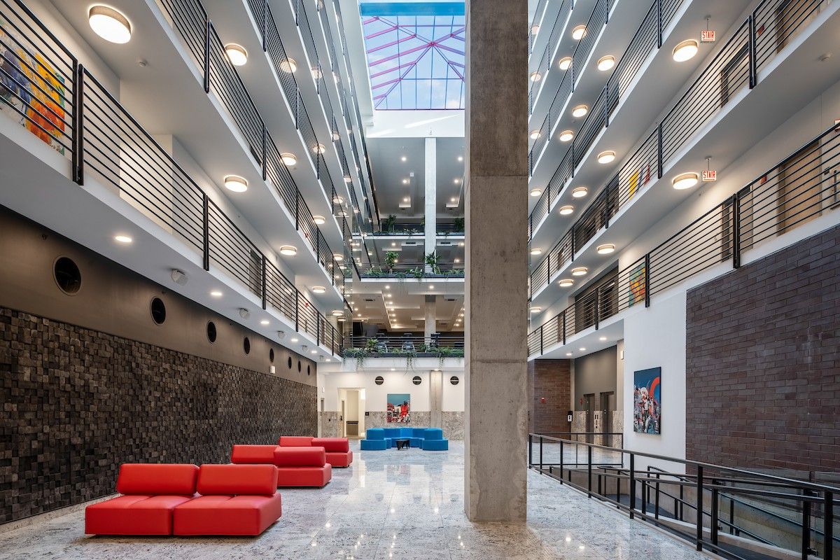 Optima Lakeview® Apartments in Chicago, IL Modern building atrium with red couches, marble floor, balconies, and a skylight ceiling for sunlight health benefits.