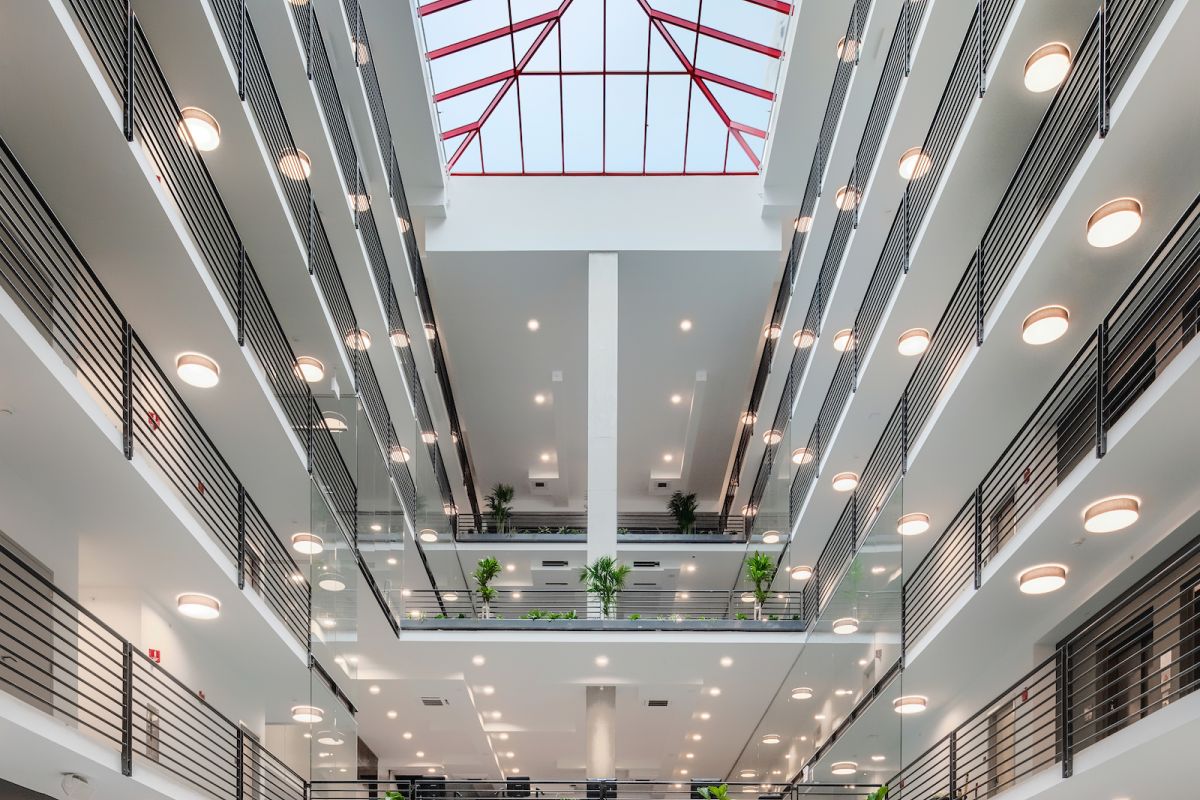 Optima Lakeview® Apartments in Chicago, IL Modern atrium with skylight, balconies, round lights, and blue seating serves as a vibrant courtyard at Optima Communities.