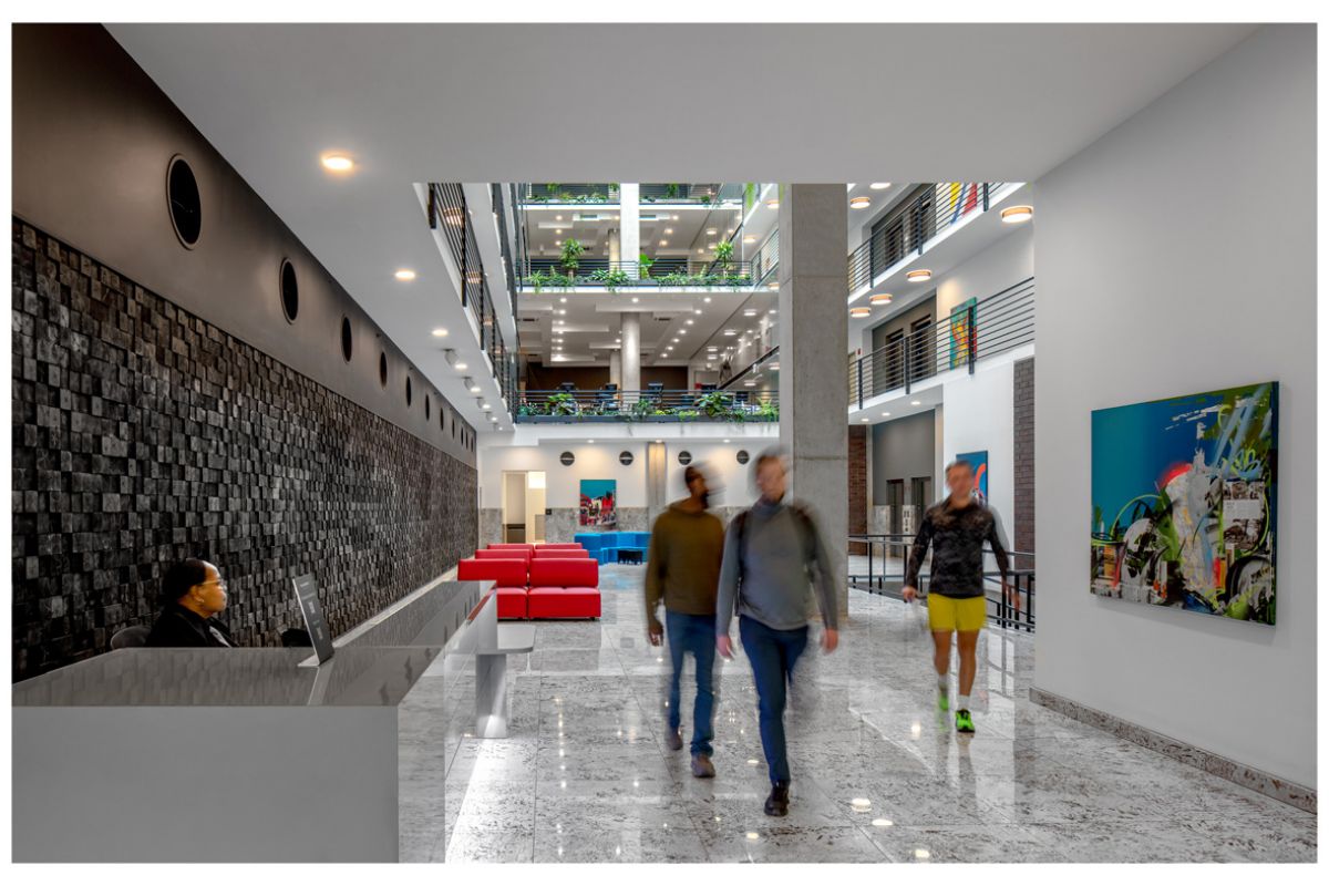 Optima Lakeview® Apartments in Chicago, IL Modern office lobby at Optima Community with people living daily life, a receptionist, and colorful art on the walls.