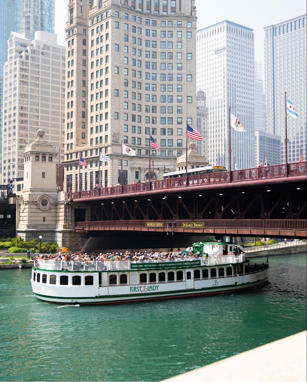 Optima Lakeview® Apartments in Chicago, IL A sightseeing boat sails on a river beneath a city bridge, offering pet families the Chicago Canine Cruise experience.