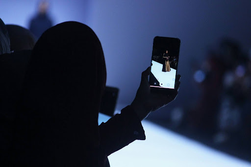 Optima Lakeview® Apartments in Chicago, IL A person snaps a photo of a model on the runway with their phone at a Chicago Fashion Week 2025 event.
