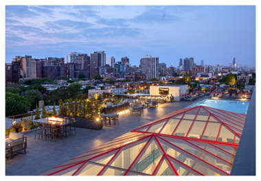 Optima Lakeview® Apartments in Chicago, IL Rooftop terrace on Optima Sky Decks with seating, fire pits, and a pool overlooking the city skyline at dusk.