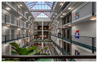 Optima Lakeview® Apartments in Chicago, IL Spacious indoor atrium with skylight, balconies, plants, and people walking—perfect for creating a relaxing home environment.