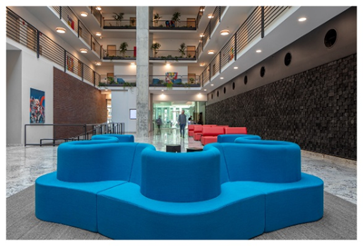 Optima Lakeview® Apartments in Chicago, IL Modern lobby with blue modular seating, red couches, indoor plants, and multi-level balconies.