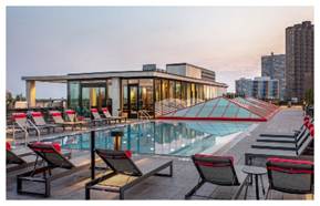 Optima Lakeview® Apartments in Chicago, IL Rooftop pool with lounge chairs, framed by modern buildings at sunset—an oasis as inviting as a perfect home sleep environment.