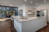 Optima Lakeview® Apartments in Chicago, IL Modern kitchen with white cabinets, marble island, stainless steel appliances, and large windows with a view.