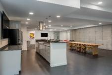 Optima Lakeview® Apartments in Chicago, IL Modern open-plan kitchen and dining area with a long wooden table and sleek, minimalist design.
