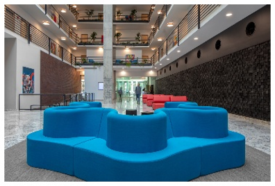 Optima Lakeview® Apartments in Chicago, IL Modern lobby at Optima Lakeview with blue modular seating, red couches, marble floors, and people near a glass entrance.